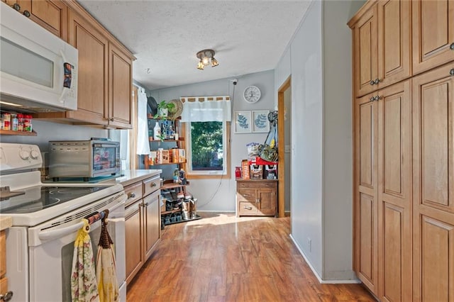 kitchen with light hardwood / wood-style floors, white appliances, a textured ceiling, and vaulted ceiling