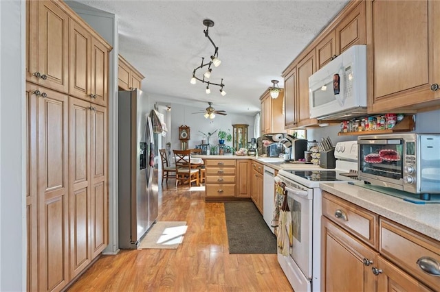 kitchen featuring kitchen peninsula, light wood-type flooring, a textured ceiling, white appliances, and ceiling fan