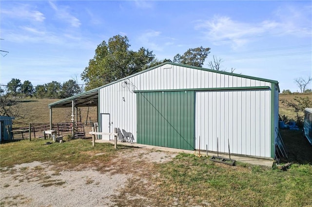 view of pole building with fence and a rural view