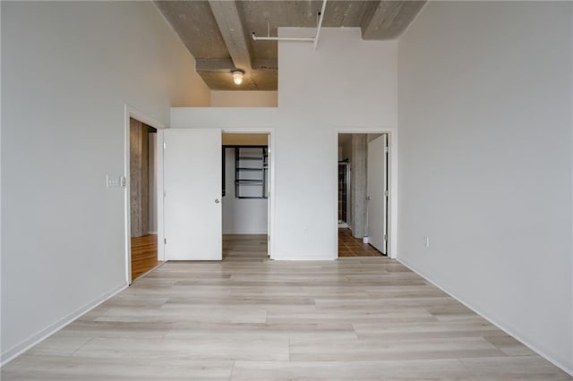 unfurnished bedroom featuring a towering ceiling and light wood-type flooring