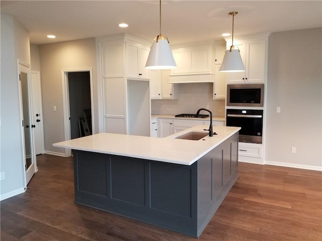 kitchen with decorative light fixtures, white cabinetry, dark hardwood / wood-style flooring, a kitchen island with sink, and stainless steel appliances