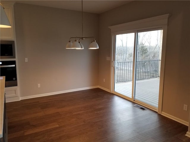 unfurnished dining area with an inviting chandelier and dark hardwood / wood-style floors