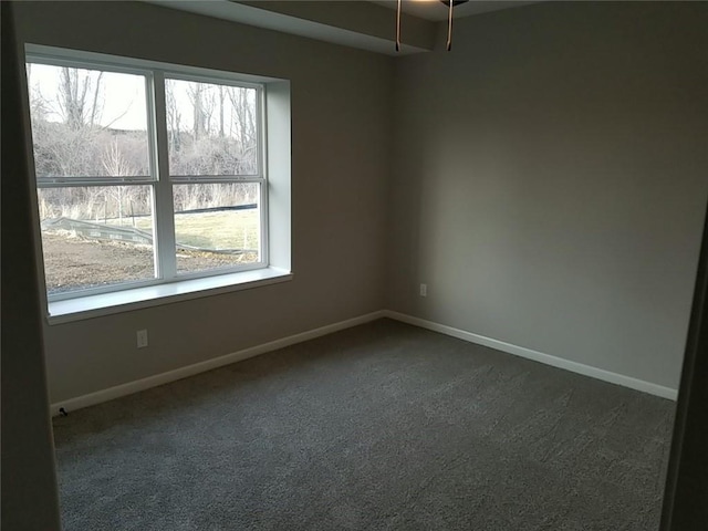 spare room with a wealth of natural light and dark colored carpet