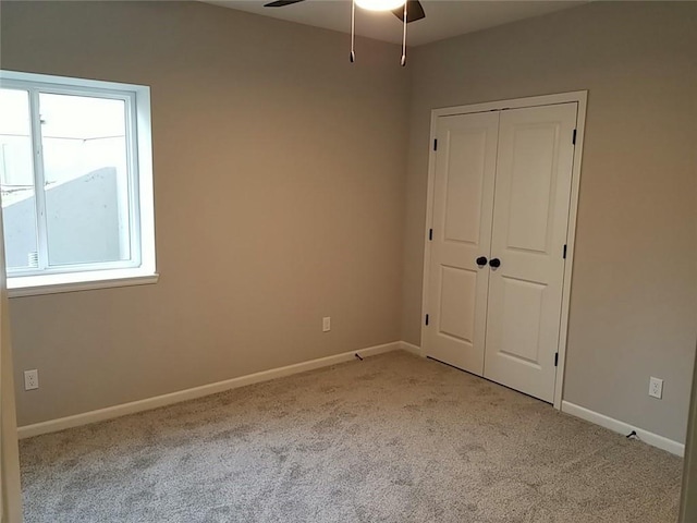 unfurnished bedroom with light colored carpet, ceiling fan, and a closet