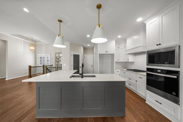 14566 Aurora Ln, Basehor, KS 66007 - kitchen featuring appliances with stainless steel finishes, a sink, white cabinets, light countertops, and a kitchen island with sink