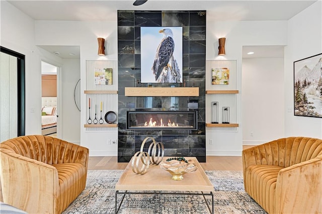 living room with light wood-type flooring and a tiled fireplace