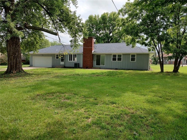 rear view of house with a lawn, cooling unit, and a garage