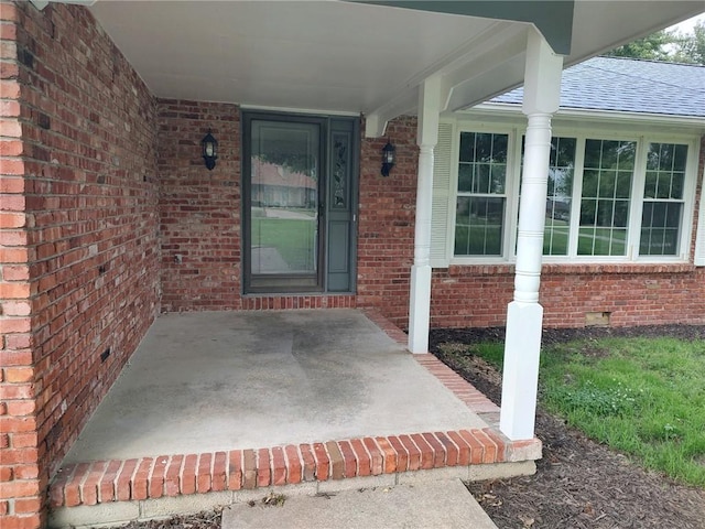 property entrance featuring crawl space, brick siding, and a shingled roof