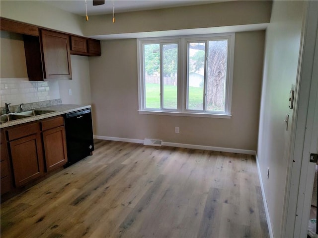 kitchen with light wood-type flooring, dishwasher, sink, backsplash, and ceiling fan