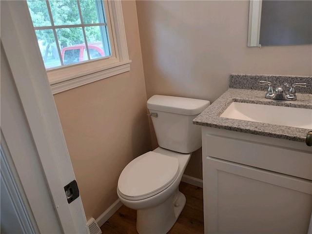 bathroom featuring baseboards, toilet, vanity, and wood finished floors
