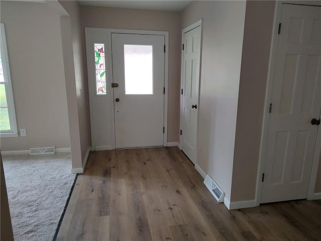 doorway with baseboards, light wood-style flooring, and visible vents