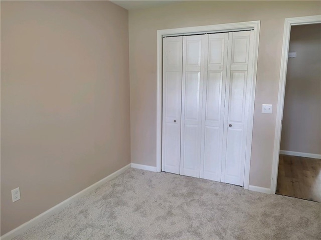 unfurnished bedroom featuring light colored carpet and a closet