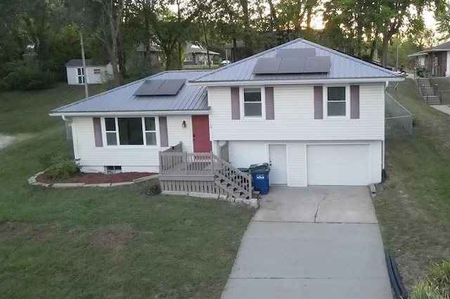 tri-level home featuring a garage, solar panels, and a yard