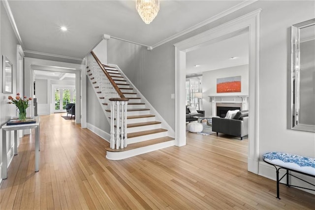 staircase with hardwood / wood-style flooring, a notable chandelier, and ornamental molding