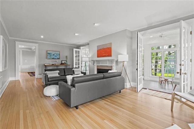 living room featuring ceiling fan, ornamental molding, light hardwood / wood-style flooring, and french doors