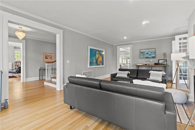 living room with crown molding, a healthy amount of sunlight, and light wood-type flooring