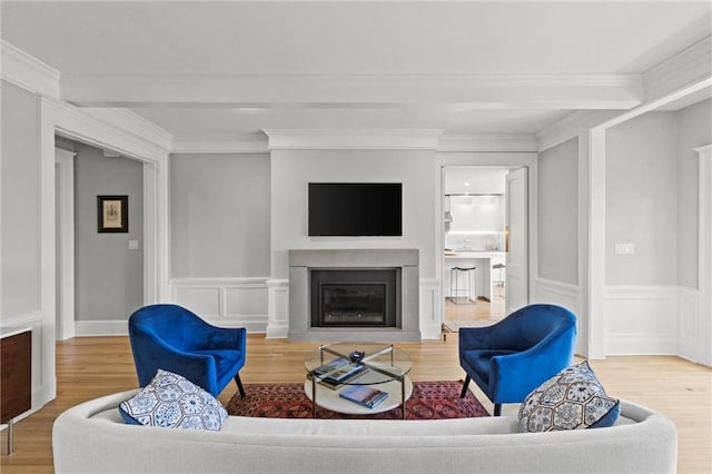 living room featuring beamed ceiling, wood-type flooring, and ornamental molding