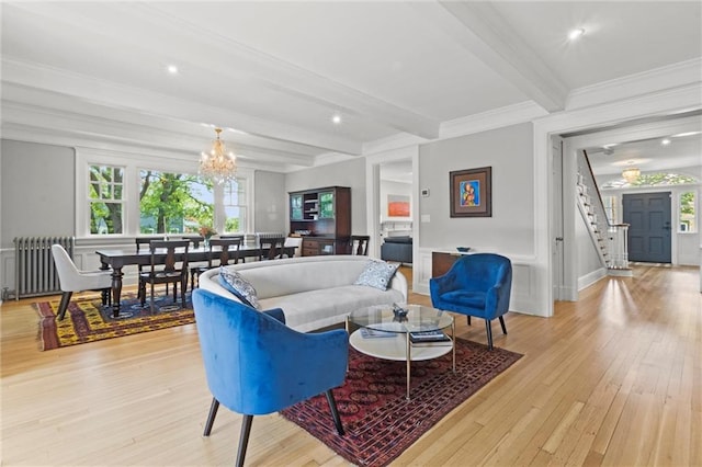 living room with radiator, crown molding, beam ceiling, light hardwood / wood-style flooring, and a chandelier