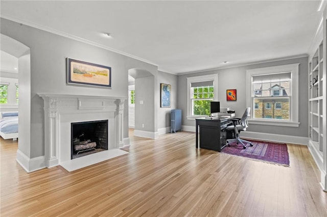 home office with built in shelves, light wood-type flooring, and ornamental molding