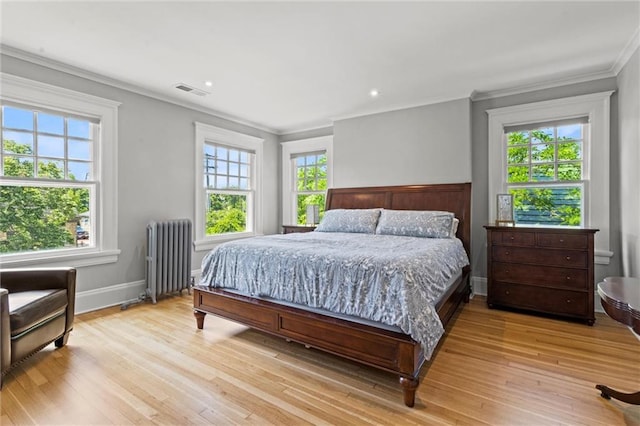 bedroom with radiator heating unit, light wood-type flooring, and ornamental molding