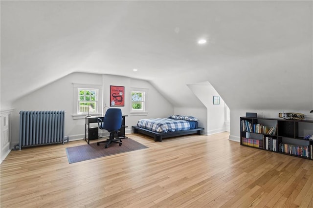 bedroom with vaulted ceiling, radiator, and light hardwood / wood-style flooring