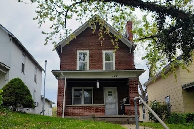 view of front of house featuring covered porch, brick siding, and a chimney