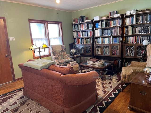 sitting room with baseboards, crown molding, and wood finished floors