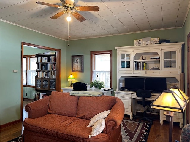 living room featuring ornamental molding, dark wood-type flooring, a ceiling fan, and baseboards