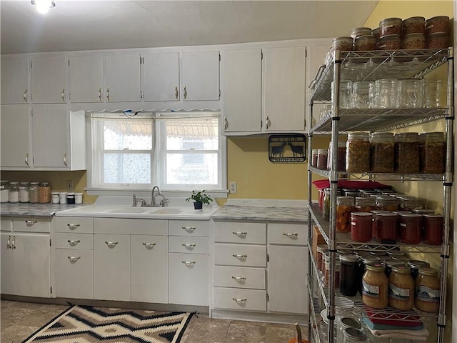 kitchen featuring white cabinets, a sink, and light countertops