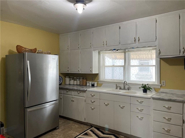 kitchen with white cabinetry, light countertops, a sink, and freestanding refrigerator