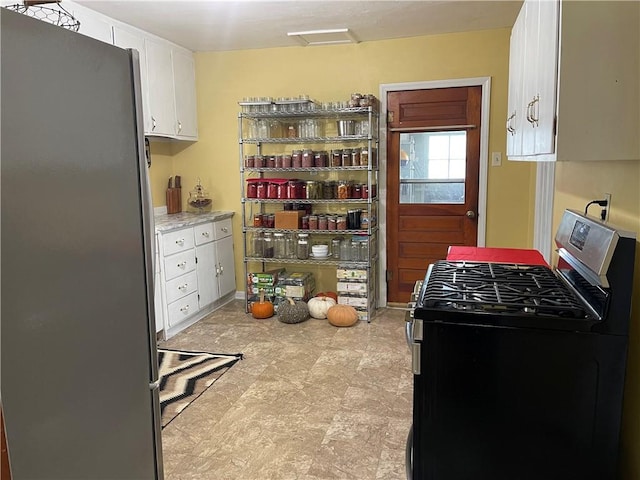 kitchen with stainless steel appliances, light countertops, and white cabinetry