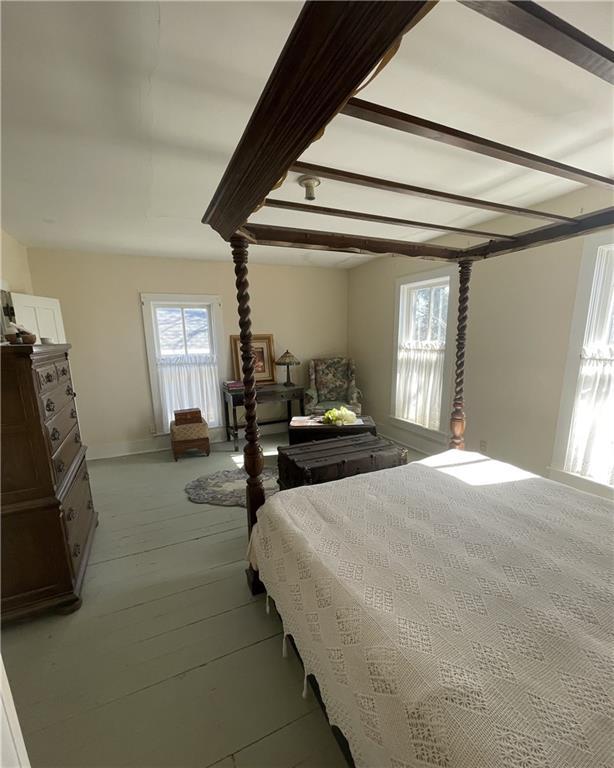 bedroom with light wood-style floors and beamed ceiling