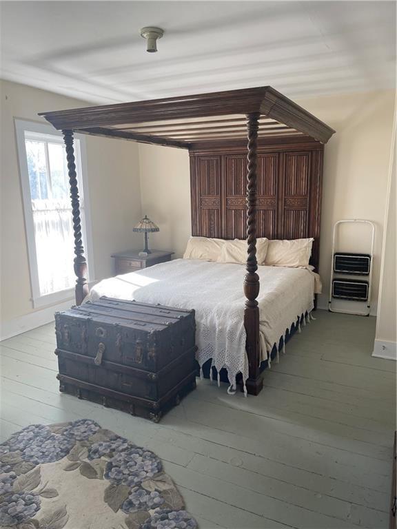 bedroom with light wood-style floors, baseboards, and heating unit