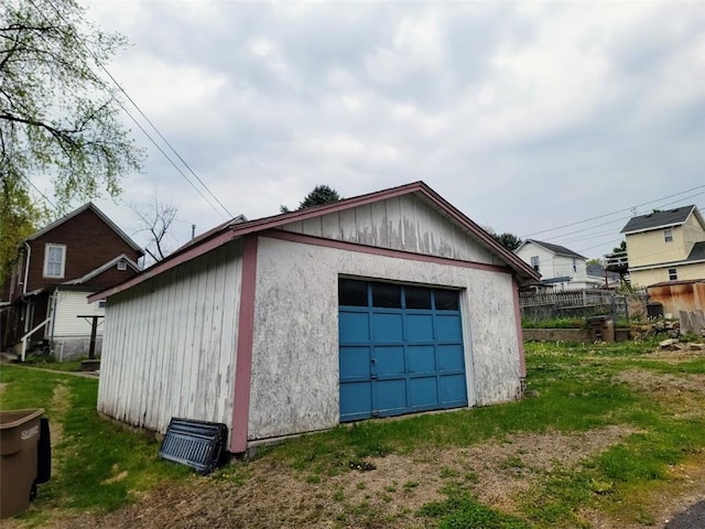 detached garage featuring driveway and fence