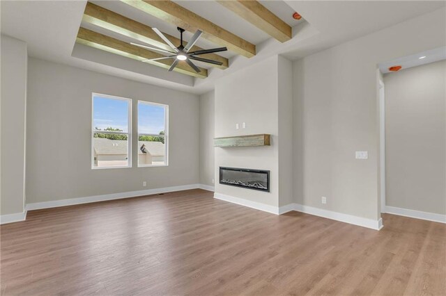 unfurnished living room with light wood-type flooring, ceiling fan, and beamed ceiling