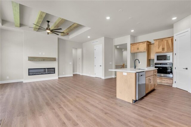 kitchen with an island with sink, stainless steel appliances, ceiling fan, and light hardwood / wood-style flooring