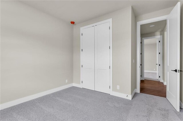 unfurnished bedroom featuring light colored carpet and a closet