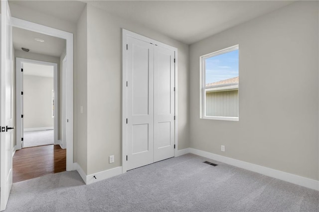 unfurnished bedroom featuring a closet and light colored carpet