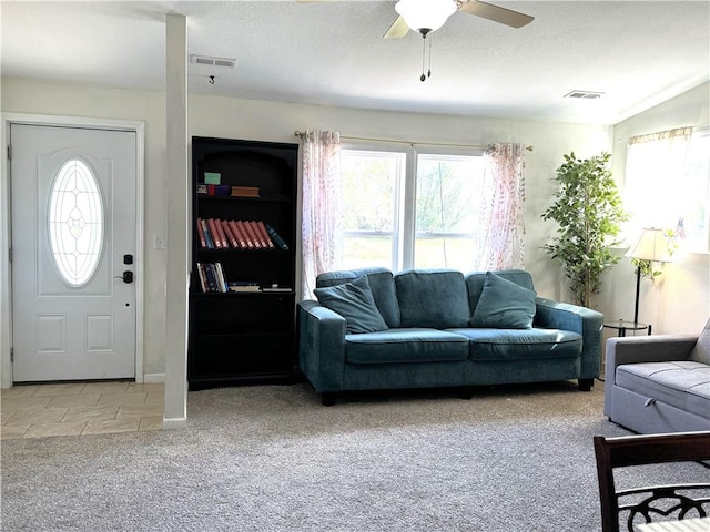 living room with light carpet, a wealth of natural light, ceiling fan, and a textured ceiling