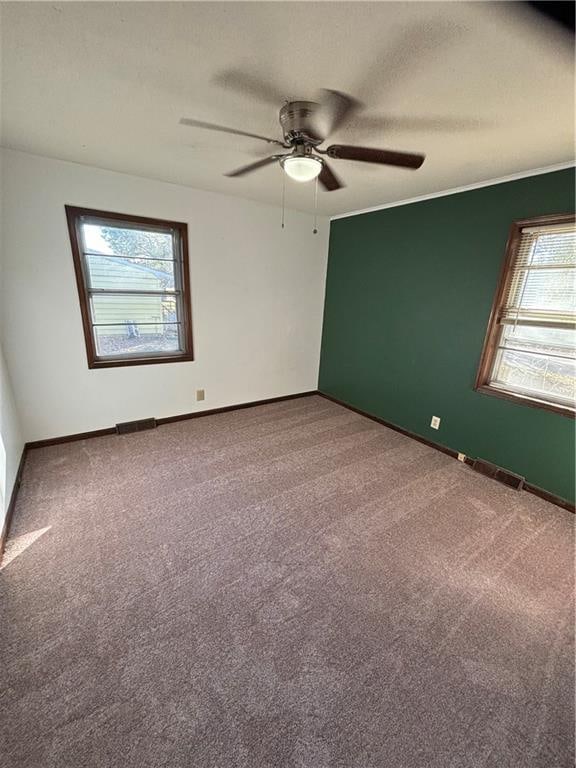 carpeted spare room featuring ceiling fan and a healthy amount of sunlight