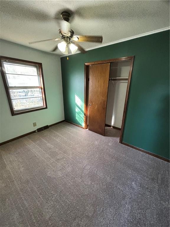 unfurnished bedroom with ceiling fan, a textured ceiling, a closet, and carpet floors