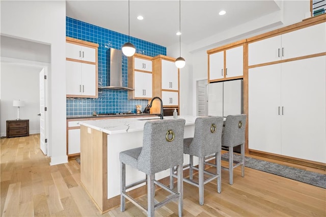 kitchen featuring hanging light fixtures, gas cooktop, white cabinets, and wall chimney exhaust hood