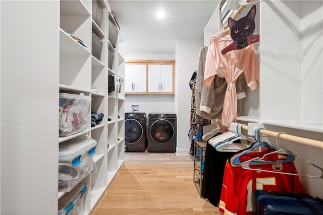 walk in closet with washing machine and clothes dryer and light hardwood / wood-style flooring