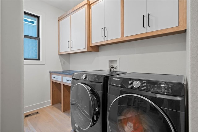 washroom with cabinets, light hardwood / wood-style floors, and washer and dryer