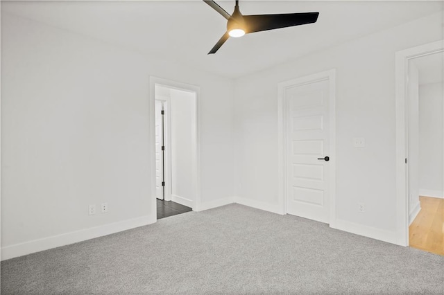 spare room with ceiling fan and dark colored carpet