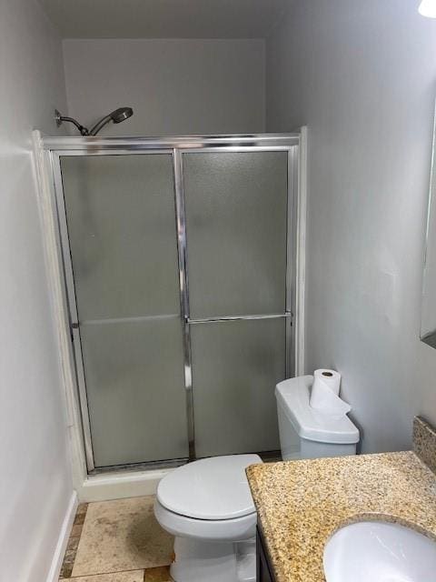 bathroom featuring tile patterned flooring, vanity, toilet, and a shower with shower door