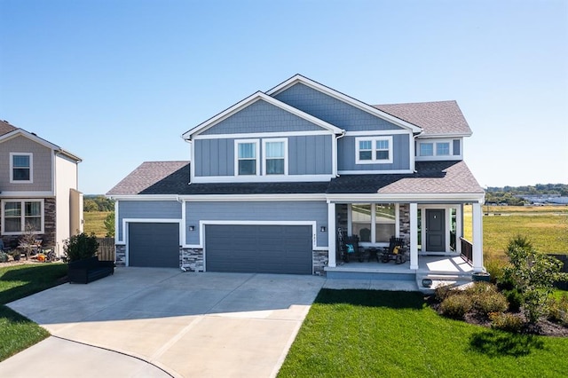 craftsman inspired home with a front yard, a garage, and covered porch