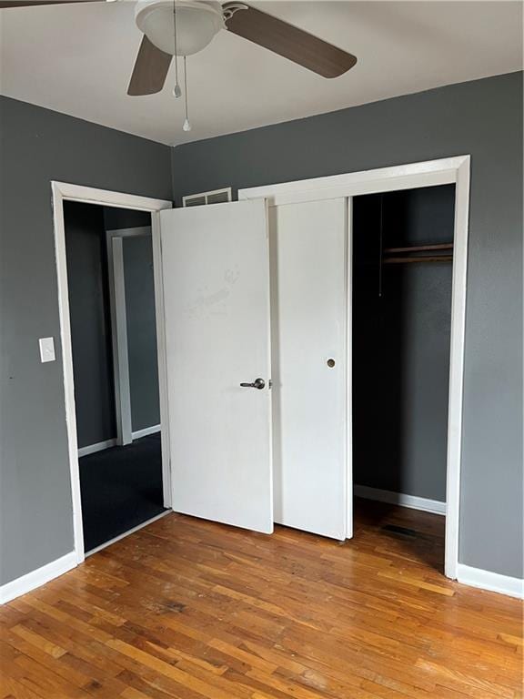 unfurnished bedroom with ceiling fan, a closet, and wood-type flooring