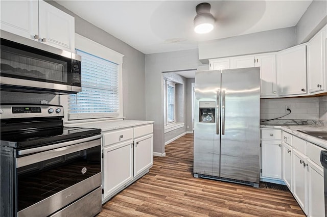 kitchen with appliances with stainless steel finishes, light wood-type flooring, and white cabinets