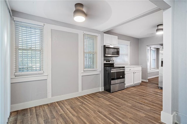 kitchen with appliances with stainless steel finishes, a wealth of natural light, and white cabinets